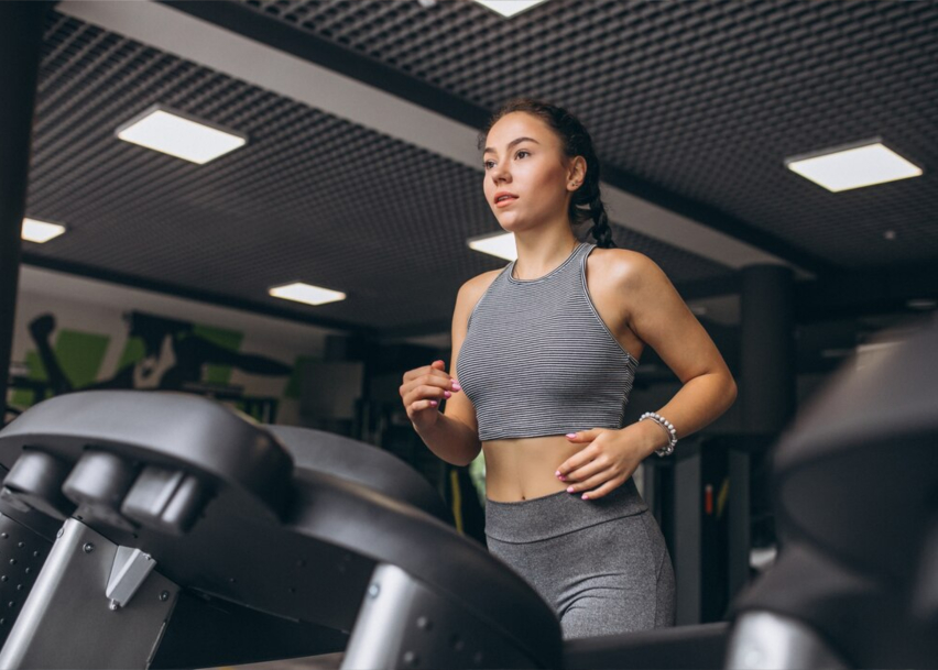 Девушка занимается кардио тренировкой на беговой дорожке